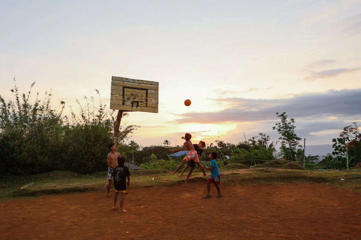 Kids playing basketball at sunset