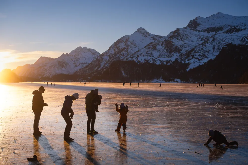 Family skating on a frozen lake at sunset