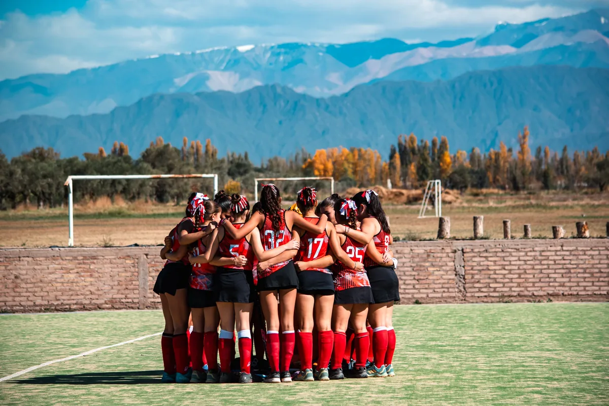 Field hockey team huddle with mountains behind