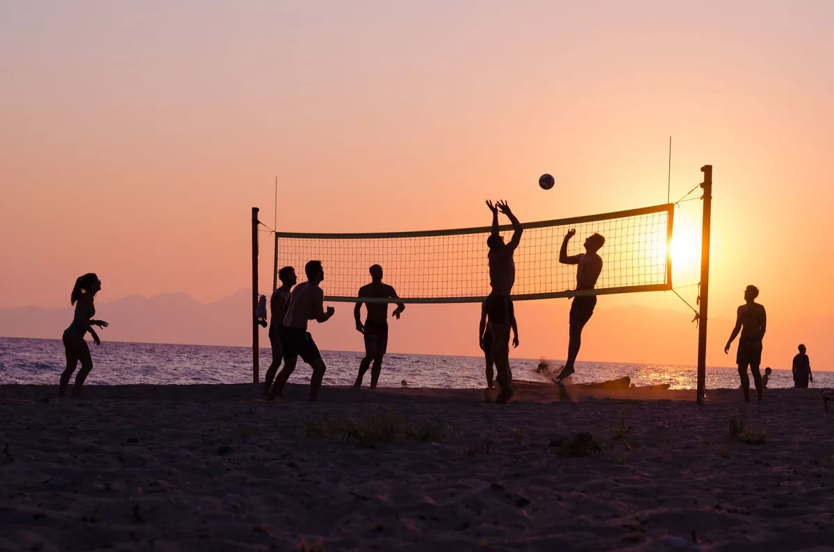 Beach volleyball game at sunset